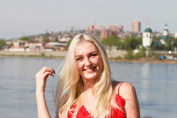 Блондинка стоит у забора на набережной реки — стоковое фото