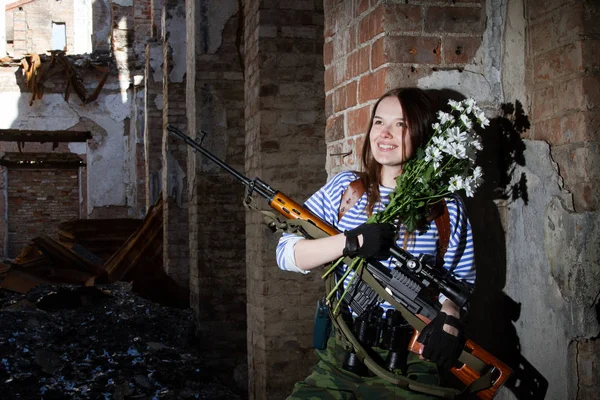 Kız keskin nişancı bir buket çiçek ile harap bir bina