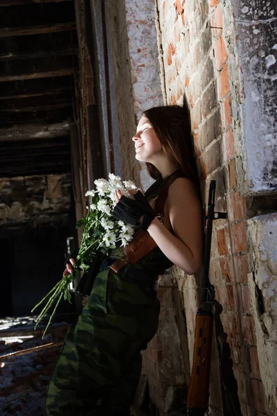 Kız keskin nişancı bir buket çiçek ile harap bir bina