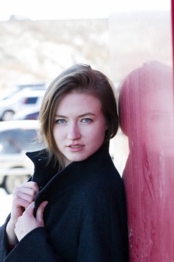 Kız bir ceket tarafından kırmızı kalkan duruyor