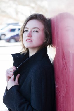 Kız bir ceket tarafından kırmızı kalkan duruyor