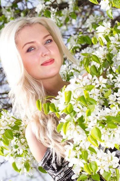 Blondin bland grenarna i ett blommande päron — Stockfoto