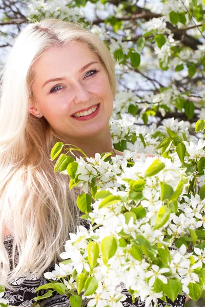 Blonde among the branches of a blossoming pear — Stock Photo, Image