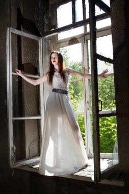 Pencere pervazına terk edilmiş evde üzerinde beyaz elbiseli ince genç kız