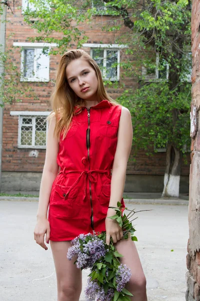 Leylak bir buket ile kısa kırmızı elbiseli kız — Stok fotoğraf