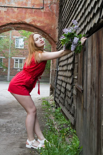 Niña en un vestido corto rojo con un ramo de color lila —  Fotos de Stock