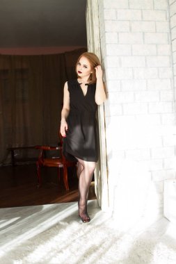 Sarışın siyah kısa bir elbise içinde kapısında duruyor