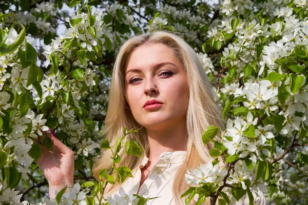 Blonde in the garden among the flowering trees — Stock Photo, Image