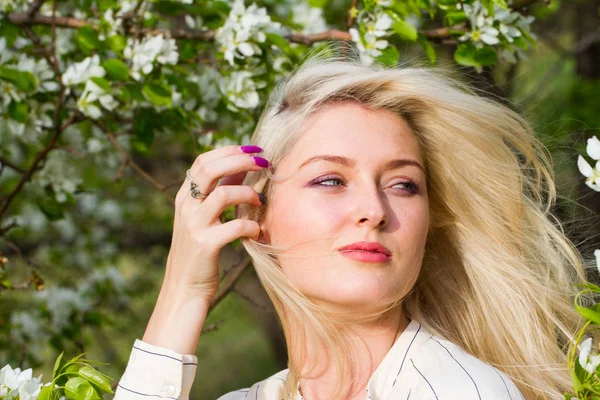 Blonde in de tuin onder de bloeiende bomen — Stockfoto