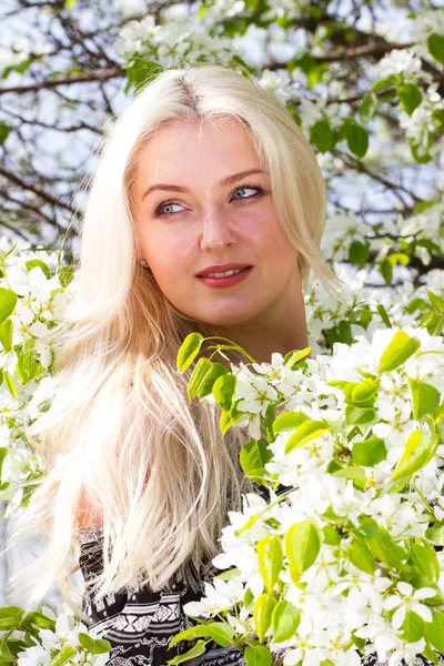 Rubia en el jardín entre los árboles florecientes — Foto de Stock