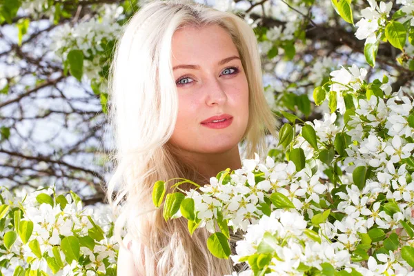 Blonde in de tuin onder de bloeiende bomen — Stockfoto