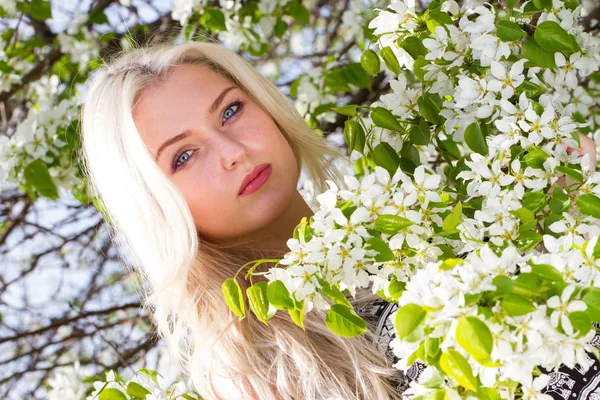 Blonde in the garden among the flowering trees — Stock Photo, Image