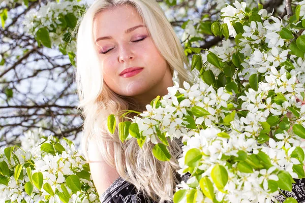 Blonde in the garden among the flowering trees — Stock Photo, Image
