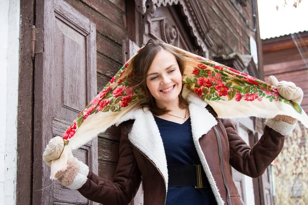 Mädchen mit buntem Schal steht auf der Veranda eines alten Holzhauses — Stockfoto