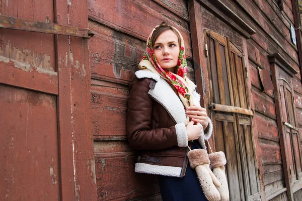 Mädchen mit buntem Schal steht auf der Veranda eines alten Holzhauses — Stockfoto