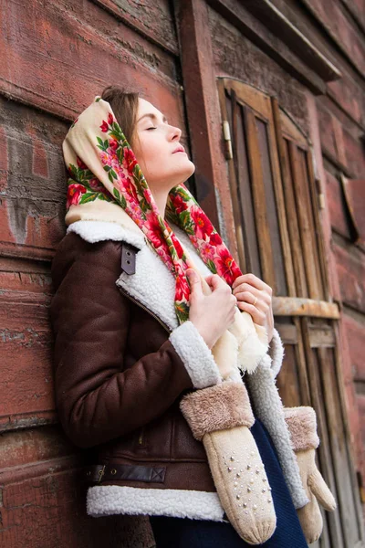 カラフルなスカーフの女の子は古い木造住宅のポーチに立っています。 — ストック写真