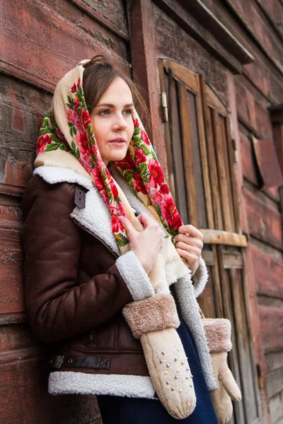 Mädchen mit buntem Schal steht auf der Veranda eines alten Holzhauses — Stockfoto