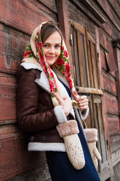 Mädchen mit buntem Schal steht auf der Veranda eines alten Holzhauses — Stockfoto