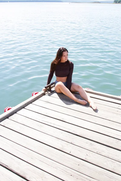 Schlankes Mädchen in kurzen Shorts auf der Seebrücke — Stockfoto