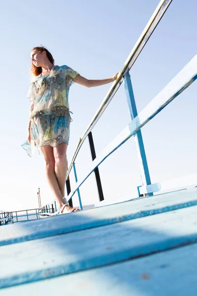 Lone slim girl stands on the pier and peers into the sea — Stock Photo, Image