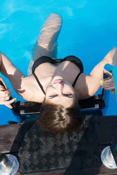 Молода дівчина в чорному купальнику купається в басейні — стокове фото