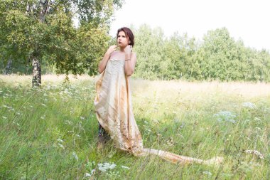 Kız uzun boylu otlar ve uzun bir gece elbisesi içinde kır çiçekleri arasında