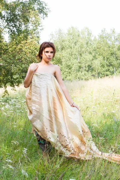 Girl among tall herbs and wildflowers in a long evening dress — Stock Photo, Image