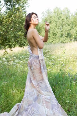 Kız uzun boylu otlar ve uzun bir gece elbisesi içinde kır çiçekleri arasında