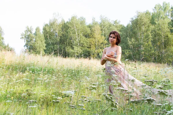 Girl among tall herbs and wildflowers in a long evening dress — Stock Photo, Image