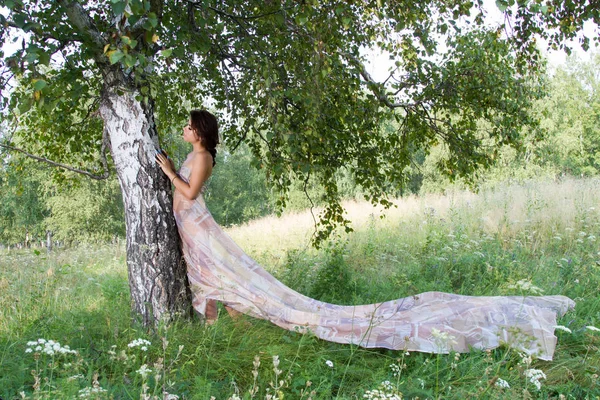 Mädchen zwischen hohen Kräutern und Wildblumen im langen Abendkleid — Stockfoto