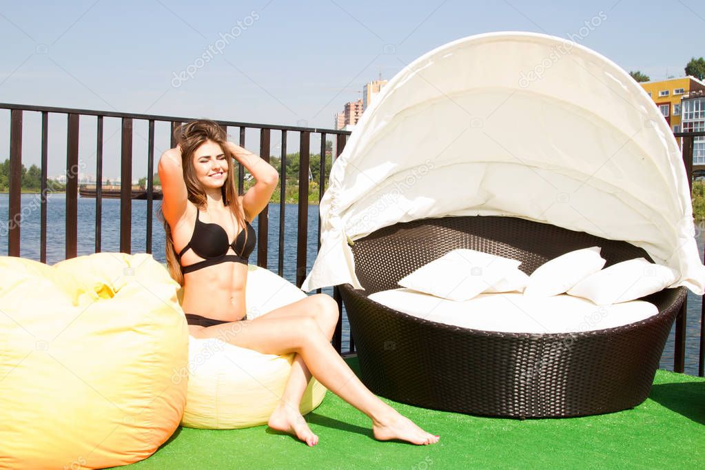 Slim girl in a black swimsuit sunbathing under the summer sun