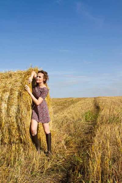 Kız lastik çizme ve mini etek bir saman balya duruyor