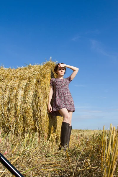Kız lastik çizme ve mini etek bir saman balya duruyor