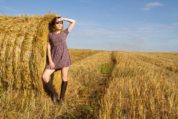 Kız lastik çizme ve mini etek bir saman balya duruyor