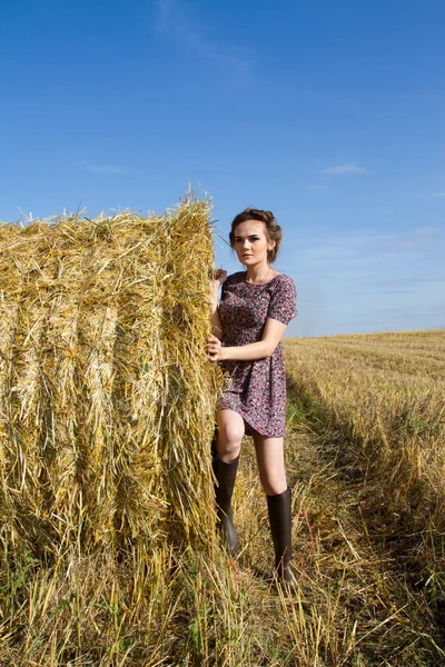 Giovane ragazza sul campo vicino a una balla di paglia — Foto Stock