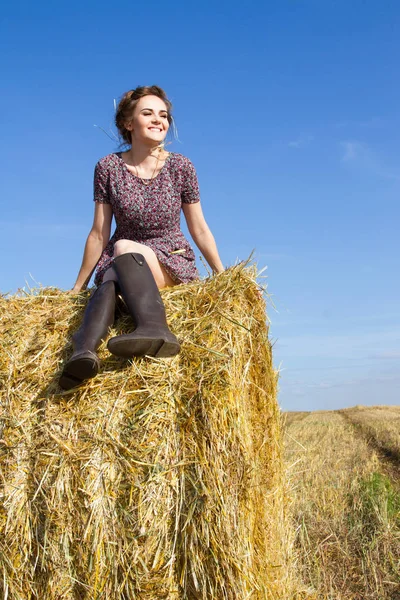 Chica joven en el campo cerca de una paca de paja —  Fotos de Stock