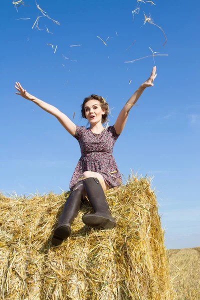 Ung flicka på fältet nära en halm bal — Stockfoto