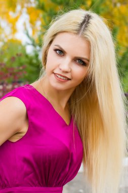 Sarı sonbahar yaprakları çerçevede bir parlak elbiseli genç sarışın