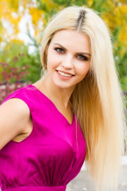 Sarı sonbahar yaprakları çerçevede bir parlak elbiseli genç sarışın