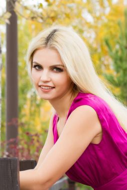 Sarı sonbahar yaprakları çerçevede bir parlak elbiseli genç sarışın