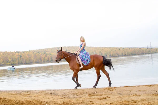 Bir göl kıyısında bir atlı bir akşam elbiseli bir kız atlar