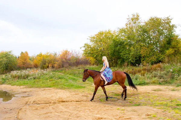 Bir göl kıyısında bir atlı bir akşam elbiseli bir kız atlar