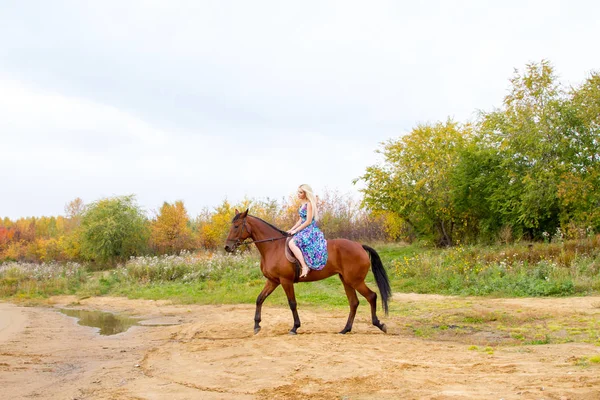 Bir göl kıyısında bir atlı bir akşam elbiseli bir kız atlar