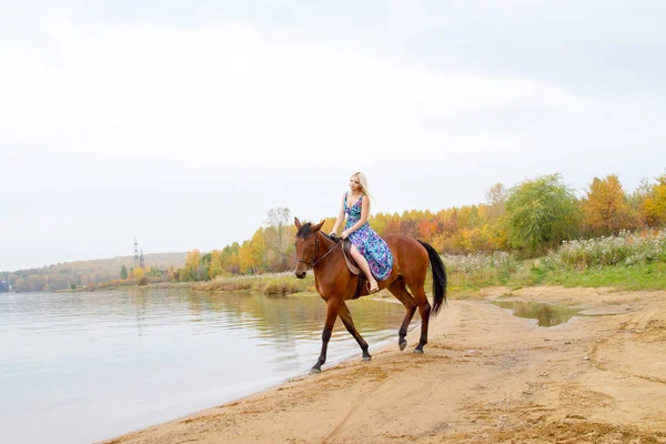 Bir göl kıyısında bir atlı bir akşam elbiseli bir kız atlar