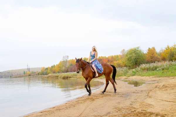 Bir göl kıyısında bir atlı bir akşam elbiseli bir kız atlar
