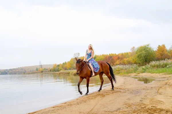 Bir göl kıyısında bir atlı bir akşam elbiseli bir kız atlar