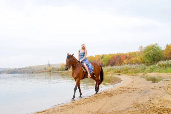 Bir göl kıyısında bir atlı bir akşam elbiseli bir kız atlar
