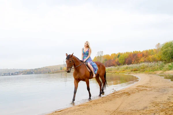 Bir göl kıyısında bir atlı bir akşam elbiseli bir kız atlar