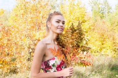 Ormanda yürüyüş kız bir buket sarı sonbahar yaprakları