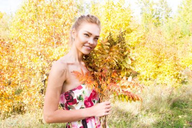 Ormanda yürüyüş kız bir buket sarı sonbahar yaprakları